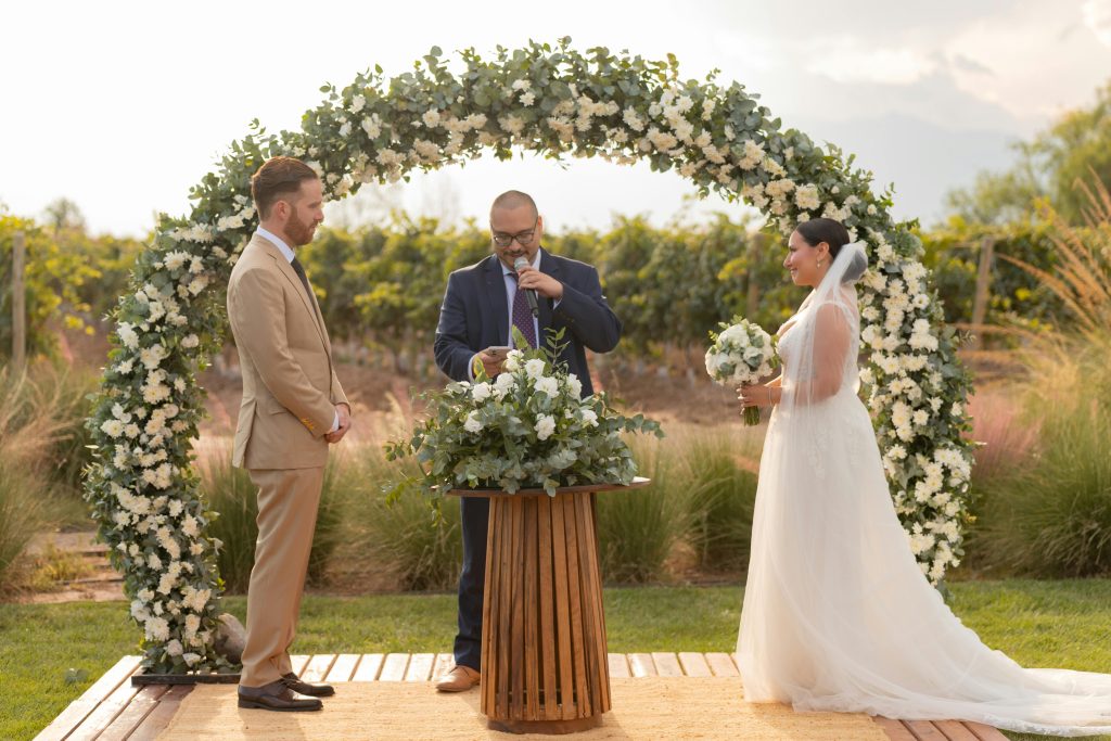 drain-cleaning Bride and groom exchange vows under a floral arch in Mendoza, Argentina vineyard.